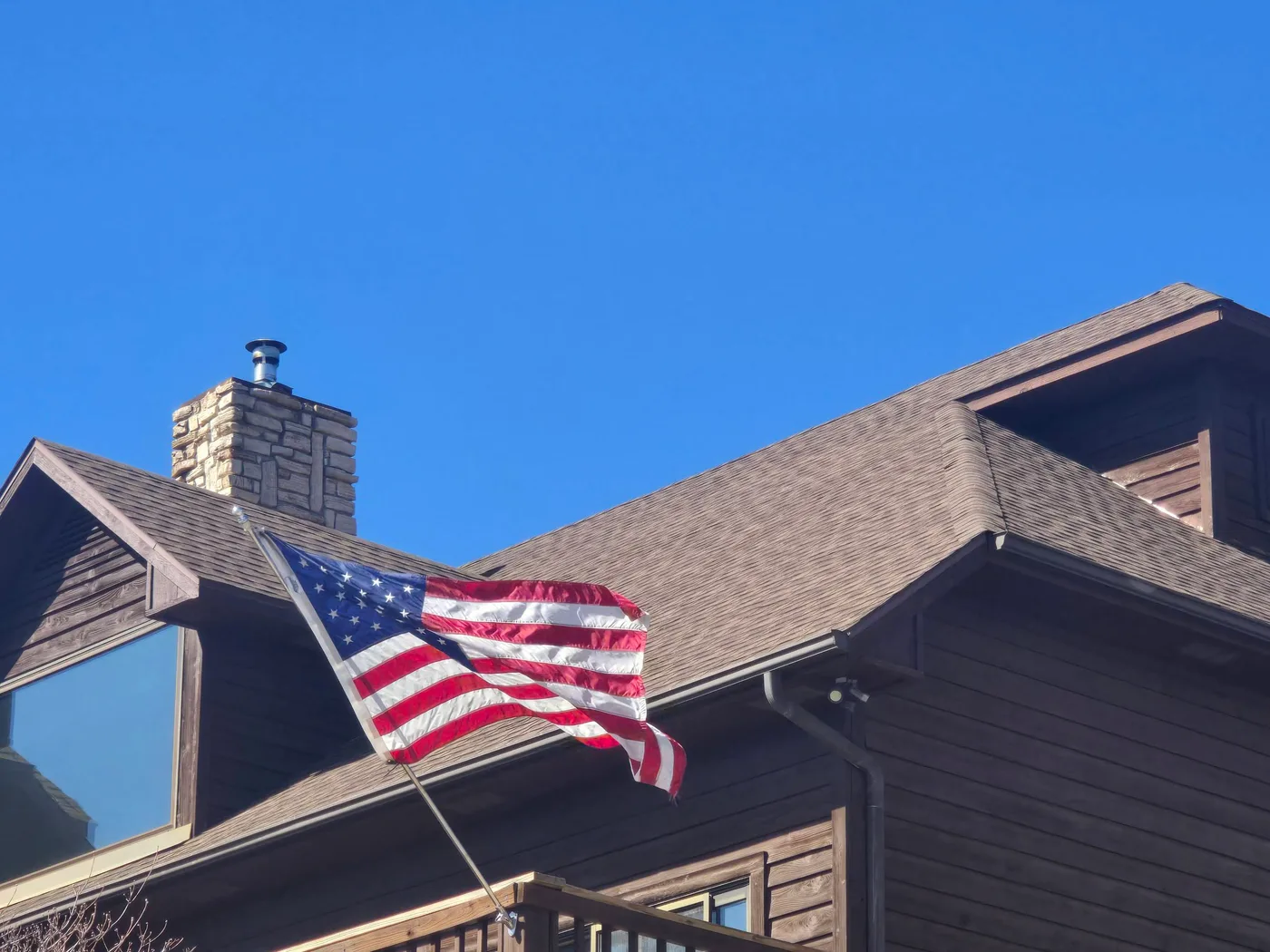 American flag flying from a home with a completed asphalt shingle roof